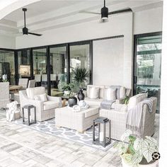 a living room filled with white furniture and lots of windows on top of a tiled floor