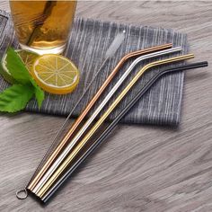 three stainless steel drinking straws on a napkin next to a glass of lemonade