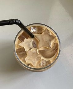 an iced drink with ice cubes and a black plastic straw in it on a white table