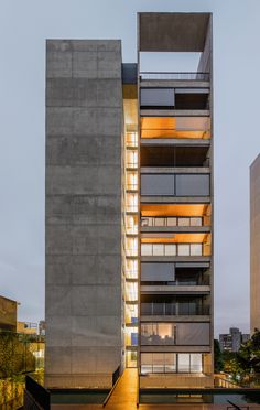 an apartment building with multiple levels and balconies on the second floor that are lit up at night