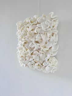 a white piece of art that looks like mushrooms on the wall, with one mushroom sticking out of it's center