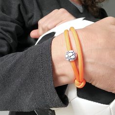 a person wearing an orange bracelet with a soccer ball on it