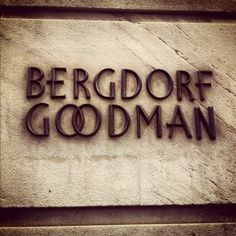 the words bergdorf goodman are carved into a stone wall with black letters on it