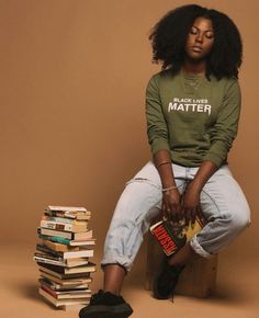 a woman sitting on top of a pile of books next to a stack of books