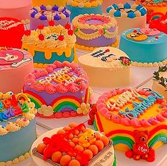 there are many different cakes on the table with frosting and icing decorations in rainbow colors