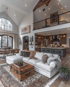 a living room filled with furniture next to a large open floor plan and lots of windows