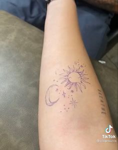 a person with a tattoo on their arm that has the sun and moon in it