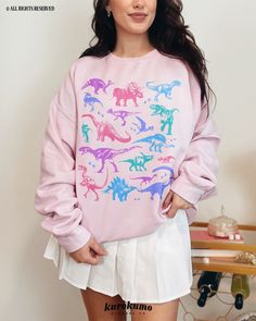 "This Unisex crewneck sweatshirt features a grunge set of dinosaur illustrations in a pastel color palette. It is the perfect gift for dinosaur lovers, present / future paleontologists, and more! Make sure to check out the other garment options below :) » O P T I O N S « ‣ Tshirt: https://www.etsy.com/listing/1699290791 » A B O U T « ‣ This item is made to order using direct-to-garment (DTG) printing technology. This digital process involves the printer inks being jetted or sprayed onto the text Casual Cotton Sweatshirt With Dinosaur Print, Casual Dinosaur Print Crew Neck Sweatshirt, Cotton Dinosaur Print Tops For Streetwear, Casual Dinosaur Print Tops For Fall, Pink Dinosaur Print Crew Neck Top, Pink Crew Neck Top With Dinosaur Print, Casual Dinosaur Print Tops For Streetwear, 90s Grunge Clothing, Soft Pastel Outfits