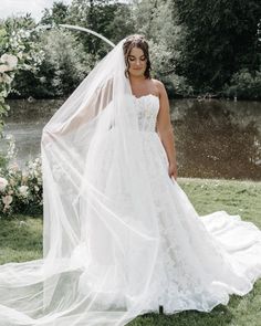 a woman wearing a wedding dress and veil standing in front of a flowered arch