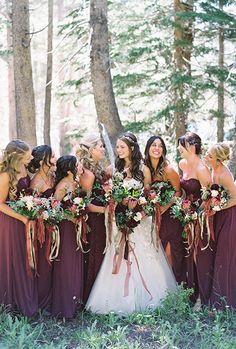 a group of women standing next to each other holding bouquets in front of trees