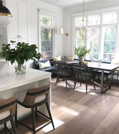 a kitchen and dining room with white cabinets, wood floors and an island in the middle