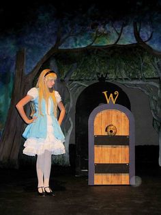 a woman in a costume standing next to a wooden door