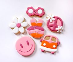 decorated cookies with pink, orange and white frosting arranged in the shape of cars