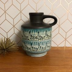 a blue and white vase sitting on top of a wooden table next to a plant