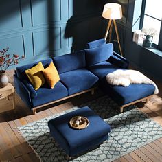 a living room with blue couches and pillows on the wooden floor, along with a dog bed