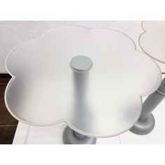 two white tables sitting on top of a tiled floor next to each other, one with a flower shaped table top