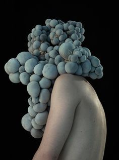 a woman with grapes on her head is standing in front of a black background,