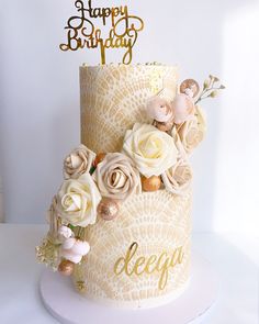 a birthday cake decorated with flowers and gold lettering