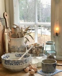 an assortment of dishes and utensils on a table in front of a window