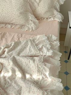 a bed with pink sheets and white ruffled bedspread