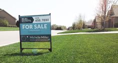 a real estate for sale sign sitting in the grass