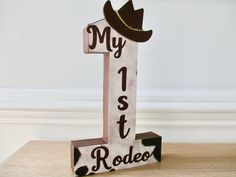 a wooden sign that says my 1st rodeo with a cowboy hat on it's top