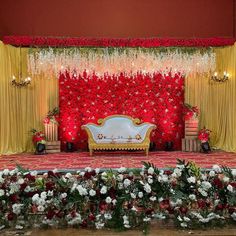 the stage is decorated with red flowers and gold drapes for an elegant wedding ceremony