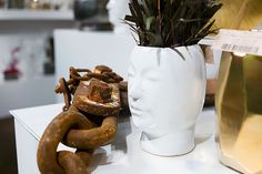 a white vase sitting on top of a table next to a chain and a plant