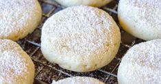 several sugar cookies cooling on a wire rack with powdered sugar sprinkles