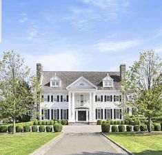 a large white house sitting on top of a lush green field