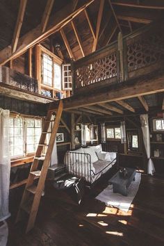 a loft with wooden walls and stairs leading up to the second floor, while a bed is in the foreground