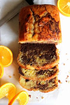 sliced loaf of orange bread sitting on top of a cutting board next to slices of oranges