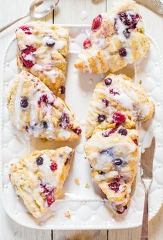 a white plate topped with scones covered in icing and cranberry toppings