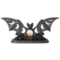 a black candle holder with a bat design on the front and an orange light in the middle