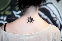 a woman with a black and white tattoo on her upper back neck is looking to the side