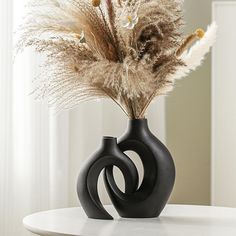 a black vase with some dried plants in it