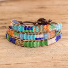 the multicolored beaded bracelet is sitting on top of a wooden table,