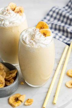 two glasses filled with banana milkshakes on top of a table