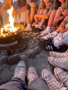 people sitting around a campfire with their feet on the ground