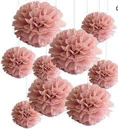 six pink tissue pom poms hanging from strings on a white background with the words,