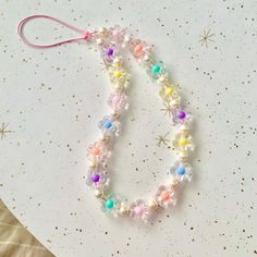 a white plate topped with a bracelet made out of glass beads and colorful beads on top of it