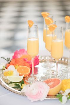 three champagne flutes filled with orange slices and garnish on a silver platter