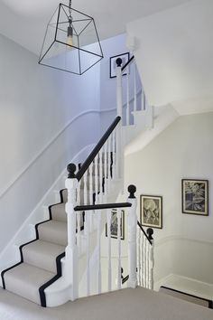 a white staircase with black handrails and framed pictures on the wall