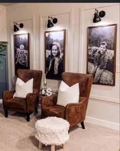 two brown chairs sitting next to each other in front of three framed pictures on the wall