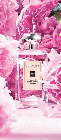 a bottle of perfume surrounded by pink flowers