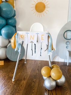 a table topped with balloons and an ironing board on top of a wooden floor