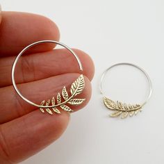 • Pair of Olive Leaf Hoop Earrings. • Cascade of gold-tone leaves w/ solid 925 sterling hoops. • 1" diameter hoops. • Backings Included. Do you have a nature lover in your life? The olive leaf earrings make a great gift! These earrings feature a sweet cascade of solid brass leaves with small 925 silver (hypoallergenic) hoops. The olive branch has been worldwide symbol of peace since ancient times, while the circle symbolizes wholeness. Give a gift of peace and wholeness. Gold Sterling Silver Hoop Earrings Nickel Free, Gold Hoop Cartilage Earrings In Sterling Silver, Minimalist Leaf-shaped Ear Wire Jewelry, Silver Huggie Earrings In Brass, Gold Sterling Silver Hoop Cartilage Earrings, Handmade Gold Hoop Earrings Nature-inspired, Leaf Hoop Earrings, Handmade Gold Nature-inspired Hoop Earrings, Silver Round Brass Hoop Earrings