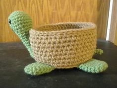 a crocheted basket with a green turtle in the middle sitting on a table