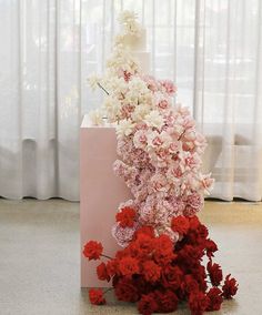 a large bouquet of flowers on top of a pink box with red and white carnations