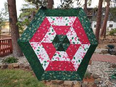 a quilted christmas ornament hanging from a tree in front of some trees